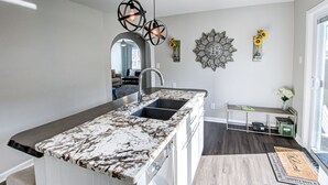 Una cocina moderna con encimera de mármol, pileta doble e iluminación colgante.