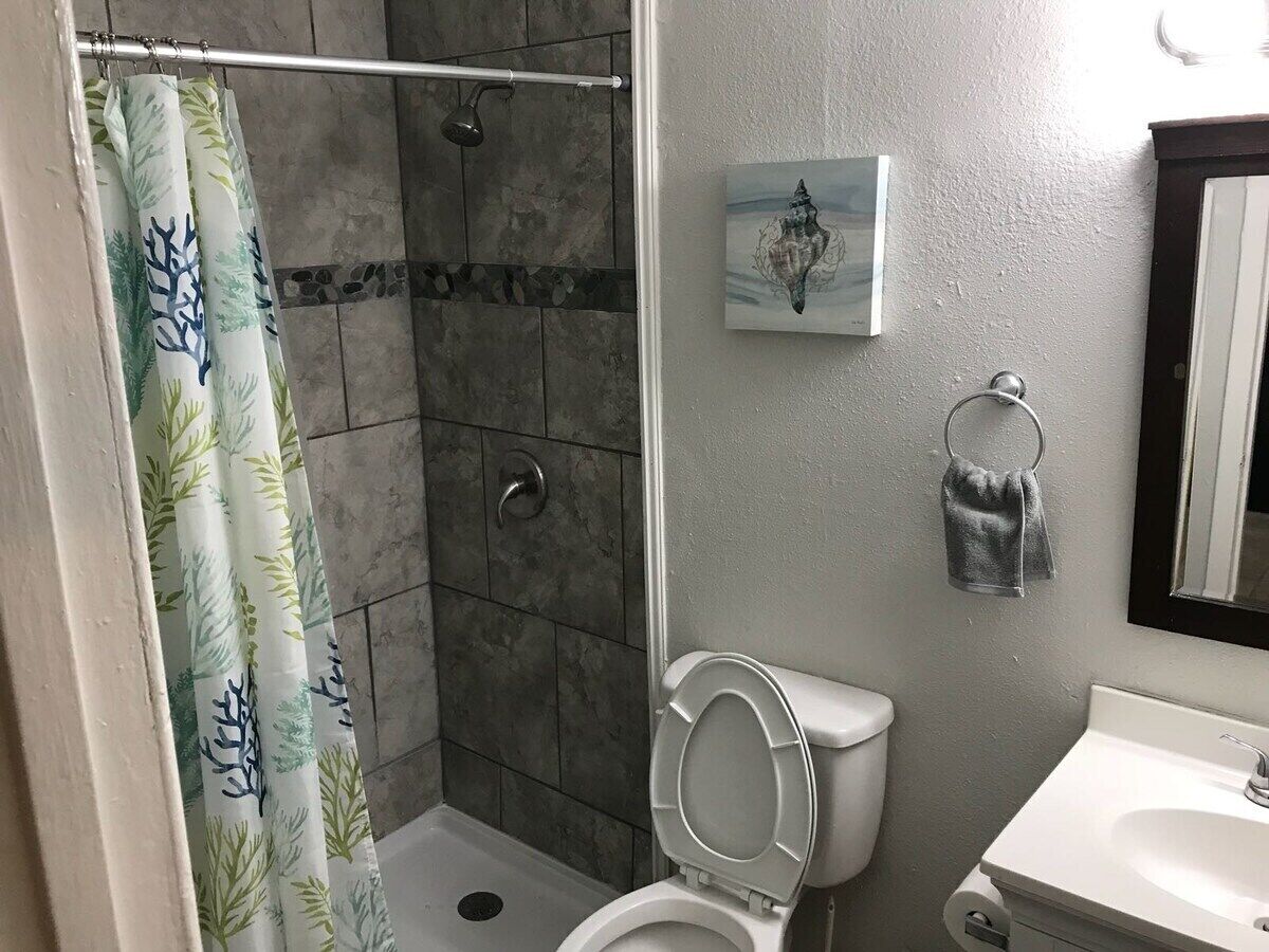 Un baño con ducha, inodoro, lavabo y toallero.