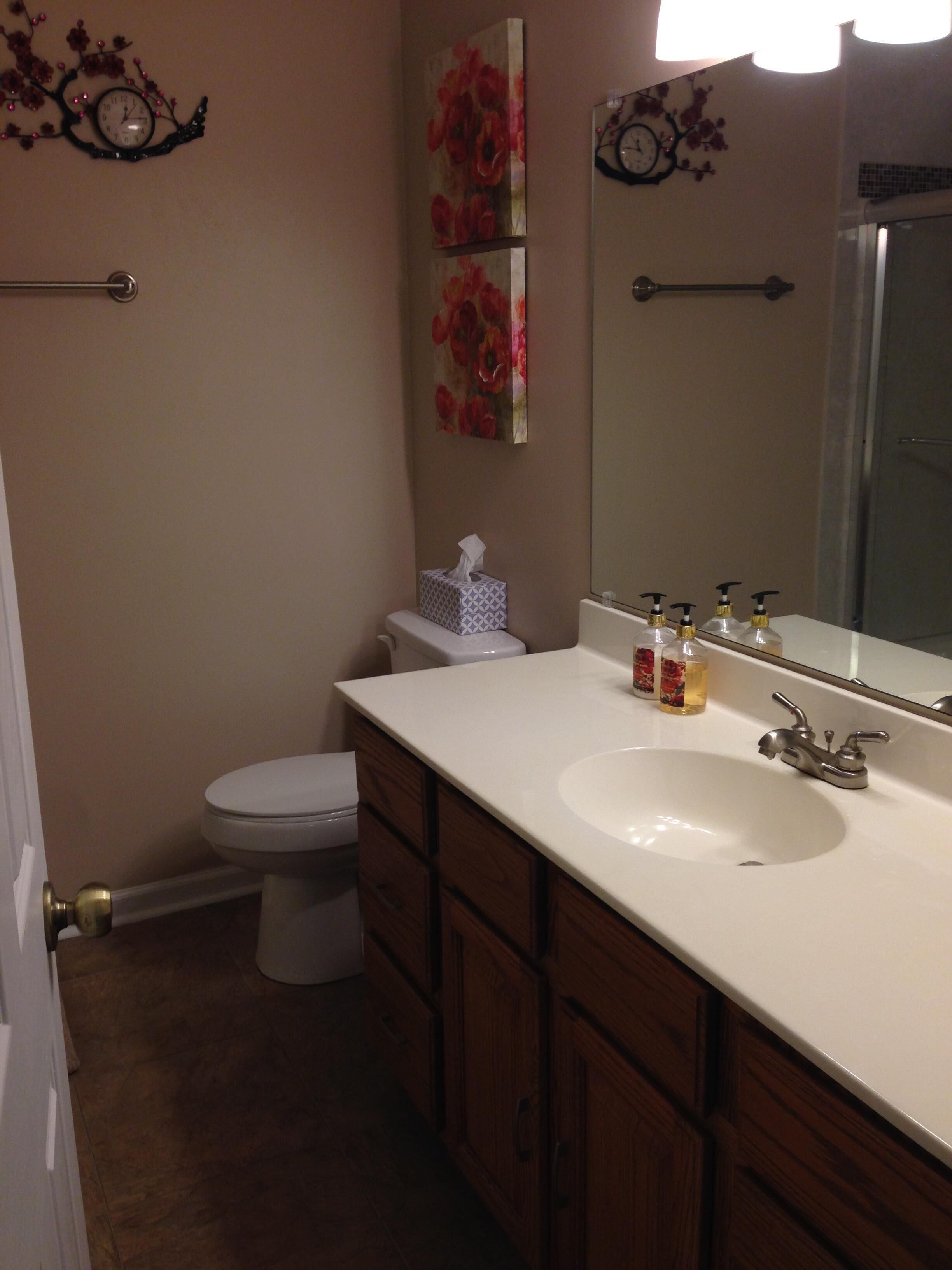 A bathroom with a white sink, wooden cabinets, a mirror, and a toilet.