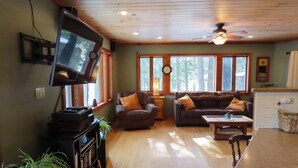Ein gemütliches Wohnzimmer mit Fernseher, zwei Sofas, einem Couchtisch und einem Bücherregal.