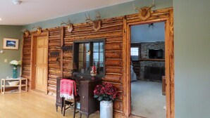 Ein rustikales Blockhaus-Interieur mit einem Holztisch, Stuhl und einem großen Spiegel.