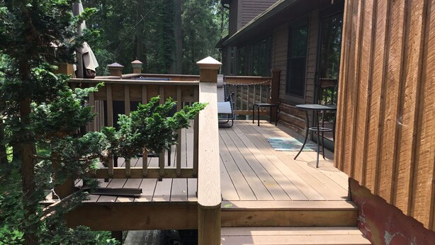 Eine Holzterrasse mit Sitzgelegenheiten im Freien und einer Treppe zu einem überdachten Bereich.