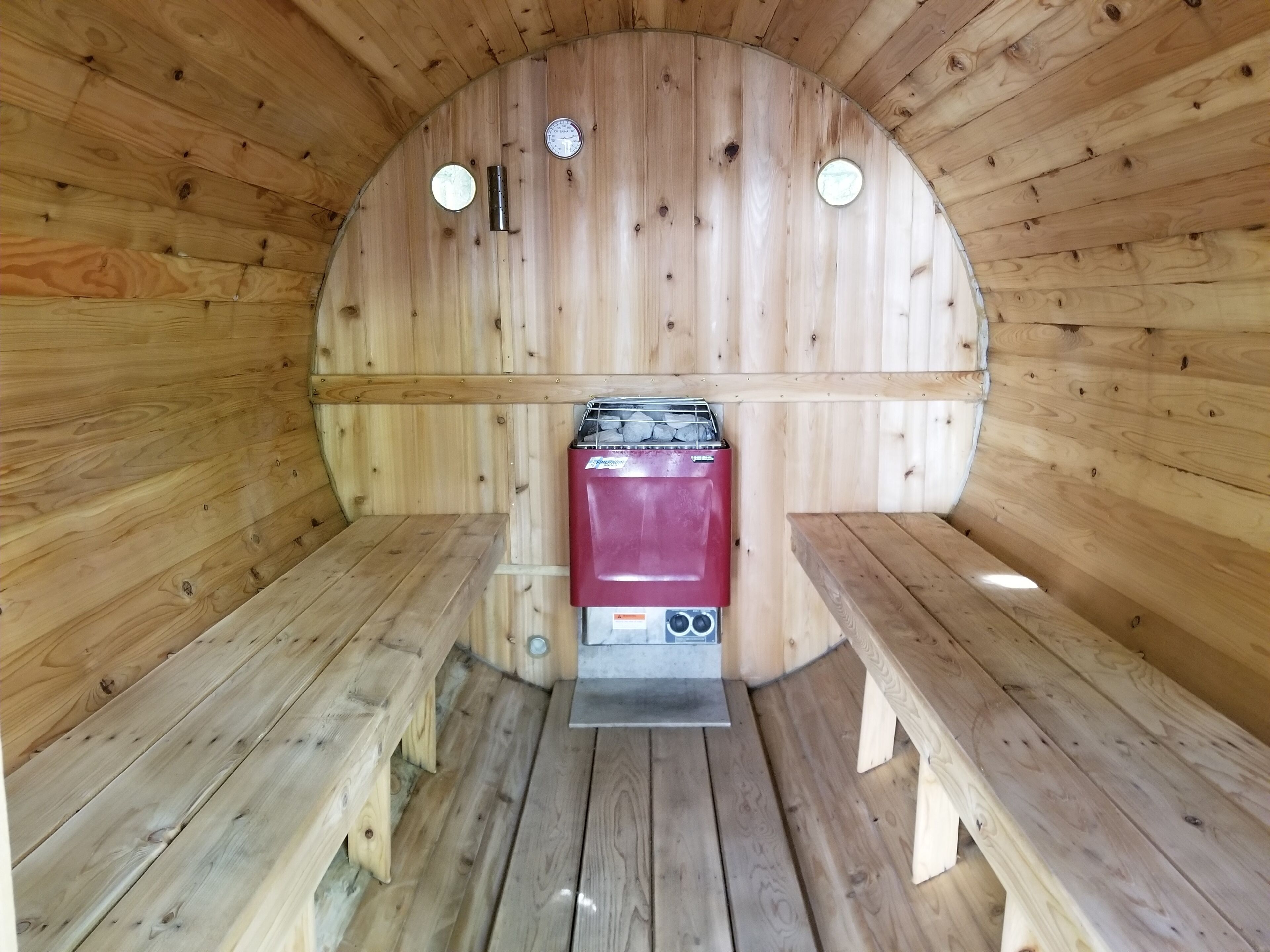 Eine Sauna mit Holzwänden, Bänken und einer Saunaanlage.