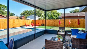 A covered patio with a pool, wicker furniture, and a view of the backyard. - Hot Tub, Pool, Game Room & Mini Golf + 2 King Beds, Fun For the Whole Family! (Tampa)