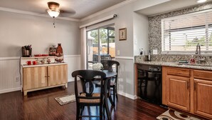 A kitchen with wooden cabinets, a dining table with chairs, a ceiling fan, and a window with blinds. - Hot Tub, Pool, Game Room & Mini Golf + 2 King Beds, Fun For the Whole Family! (Tampa)