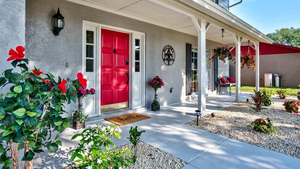 A house with a red door, a porch with white columns, and a welcome mat. - Hot Tub, Pool, Game Room & Mini Golf + 2 King Beds, Fun For the Whole Family! (Tampa)