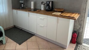 Eine Küche mit weißen Schränken, einer Holzarbeitsplatte, einer Kaffeemaschine und einem Feuerlöscher.