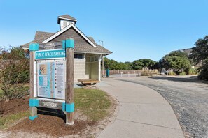 A wooden signboard for public beach parking with a map and information.
