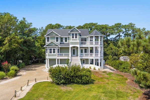 A two-story house with a wrap-around porch and a small tower-like structure on the second floor.