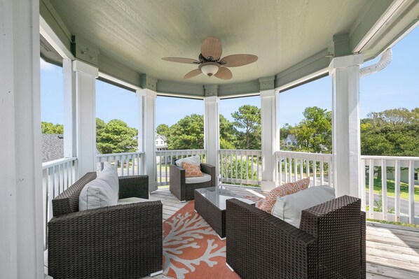 A covered porch with wicker furniture, a ceiling fan, and a view of the neighborhood. - Sweet Caroline: Saltwater Pool, Spa, Club Access (Corolla)