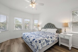 A bedroom with a bed, a nightstand, a lamp, and a ceiling fan.