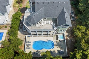 A large house with a swimming pool, multiple decks, and outdoor seating.