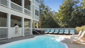 Et poolområde med pool, liggestole og en bygning med balkon.