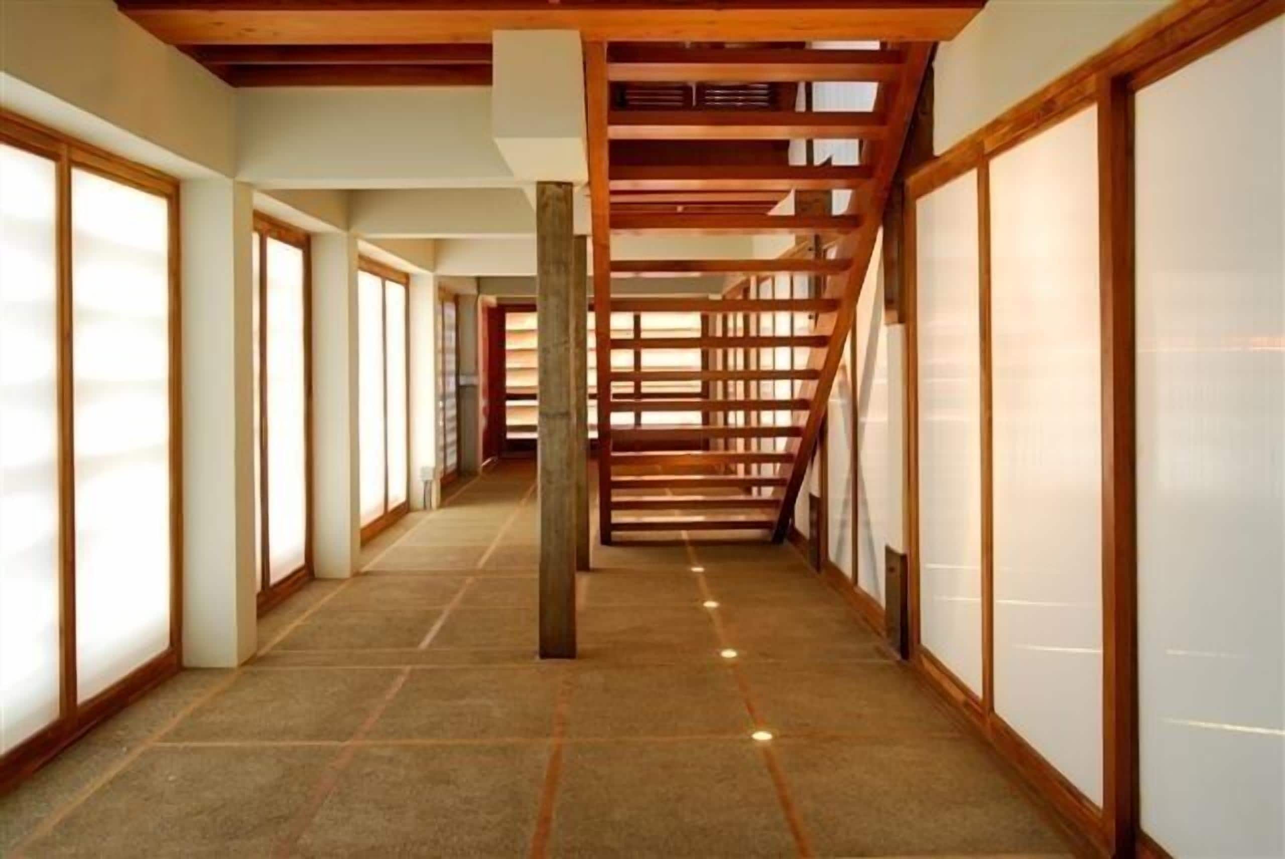 Un pasillo con vigas de madera, esteras de tatami y puertas correderas.