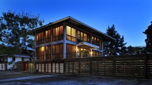 A modern two-story building with large windows and a balcony, surrounded by a wooden fence. - BirdHouse@Gamboa, Panama Canal (Gamboa)