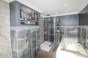 Een bad/douchecombinatie, een bubbelbad, een haardroger, handdoeken