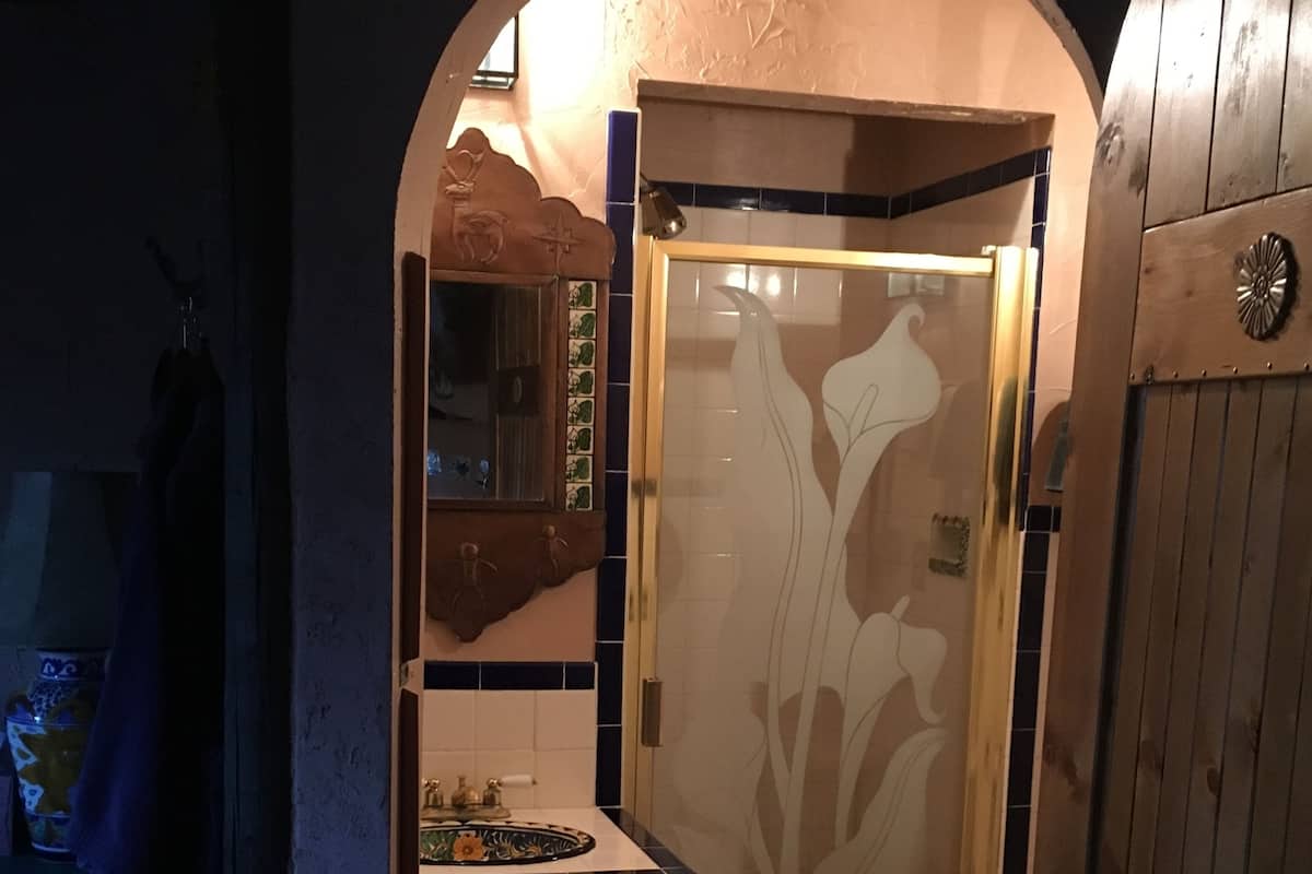 Un baño con tocador de madera, cabina de ducha de vidrio y piso de baldosas.
