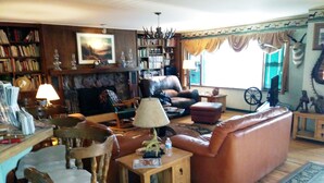A cozy living room with a fireplace, a sofa, a dining table, and a bookshelf.