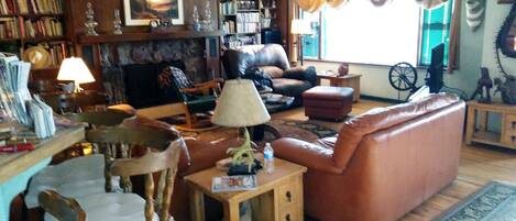 A cozy living room with a fireplace, a sofa, a dining table, and a bookshelf.
