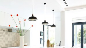 A modern kitchen with a central island, pendant lights, and a view to the outdoors.