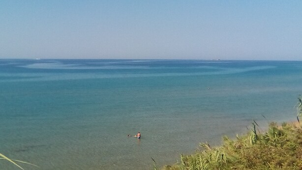 Una spiaggia con acque cristalline e una persona in lontananza.