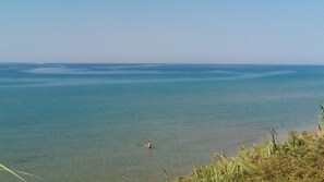 Ein Strand mit klarem Wasser und einer Person in der Ferne.