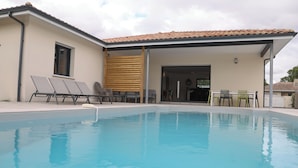 A swimming pool with lounge chairs and a covered patio area.
