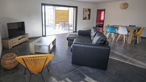 A modern living room with a sofa, TV, and dining area with chairs.