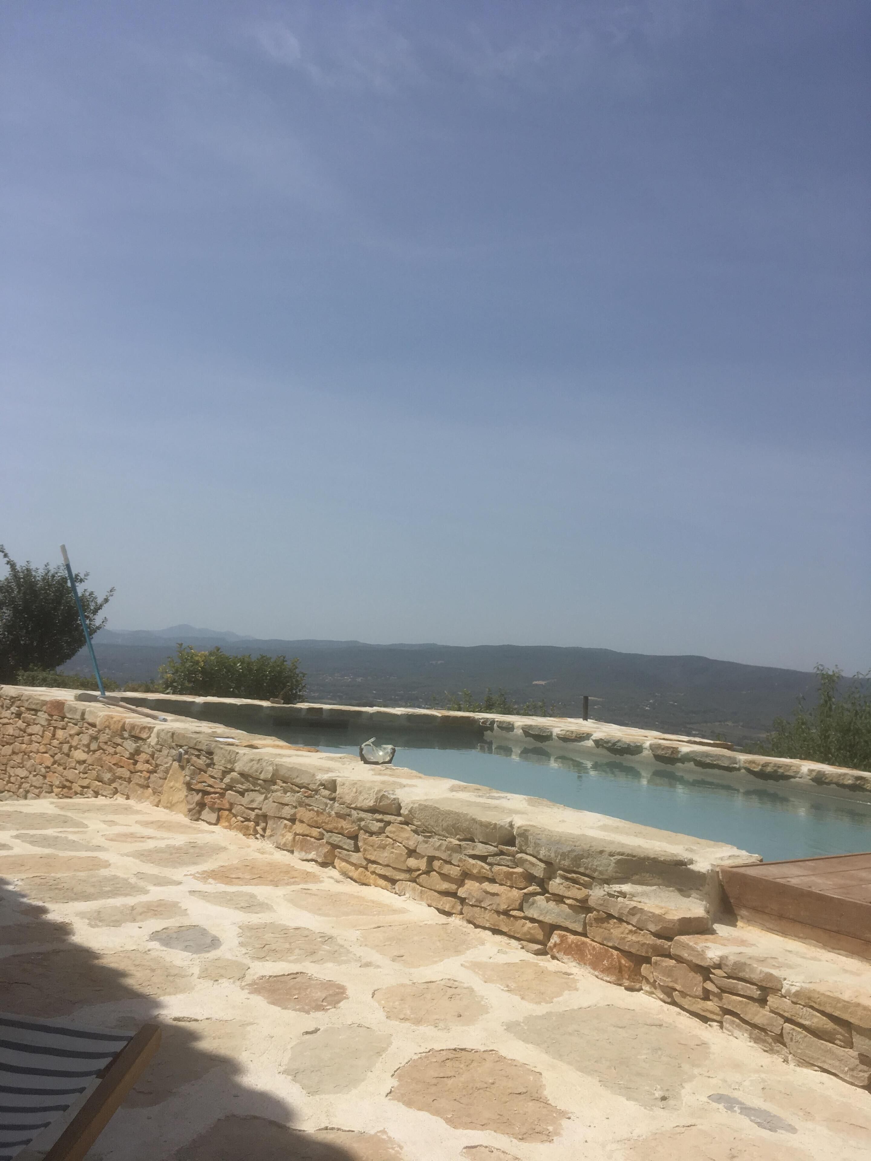 Une piscine en pierre offrant une vue dégagée sur les montagnes lointaines.