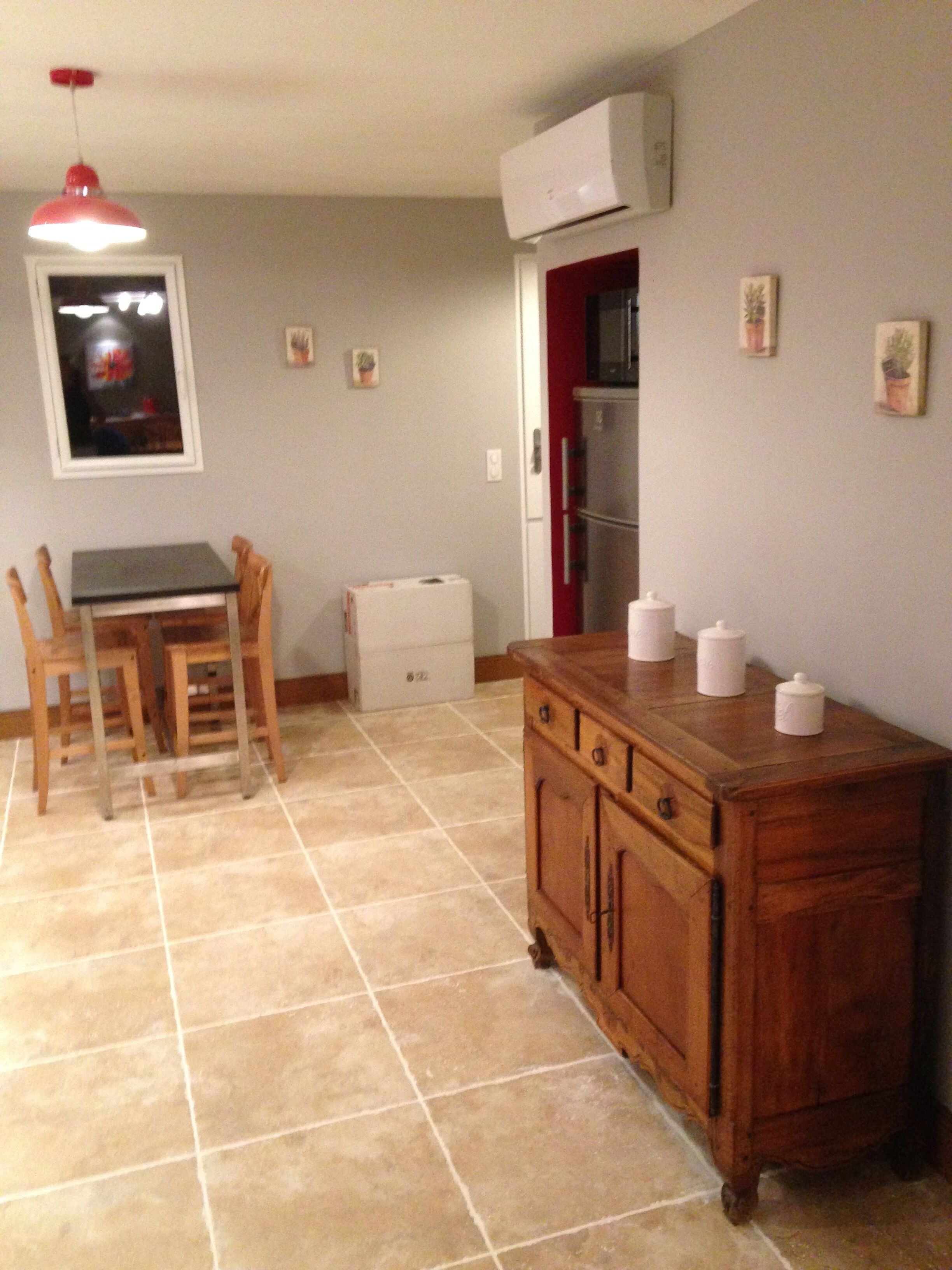 A kitchen with a dining table, chairs, a wooden cabinet, and a refrigerator.
