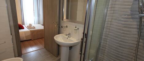 A modern bathroom with a sink, mirror, and shower.