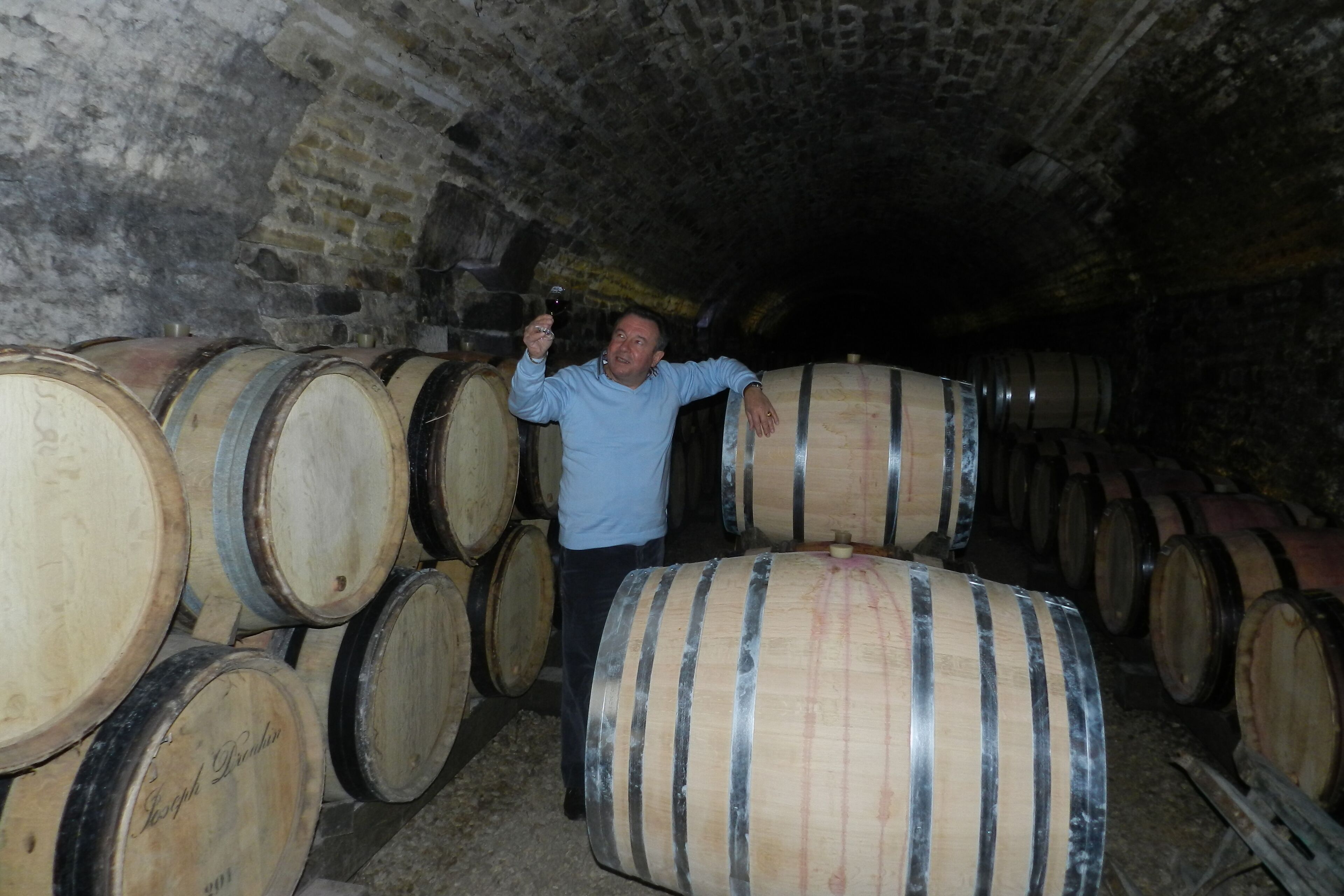 A man standing in a cellar with wooden barrels.