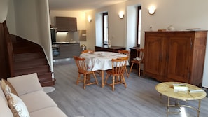 Une cuisine moderne avec des meubles en bois, une table à manger avec des chaises, un buffet en bois, un canapé et une petite table ronde avec une télécommande.