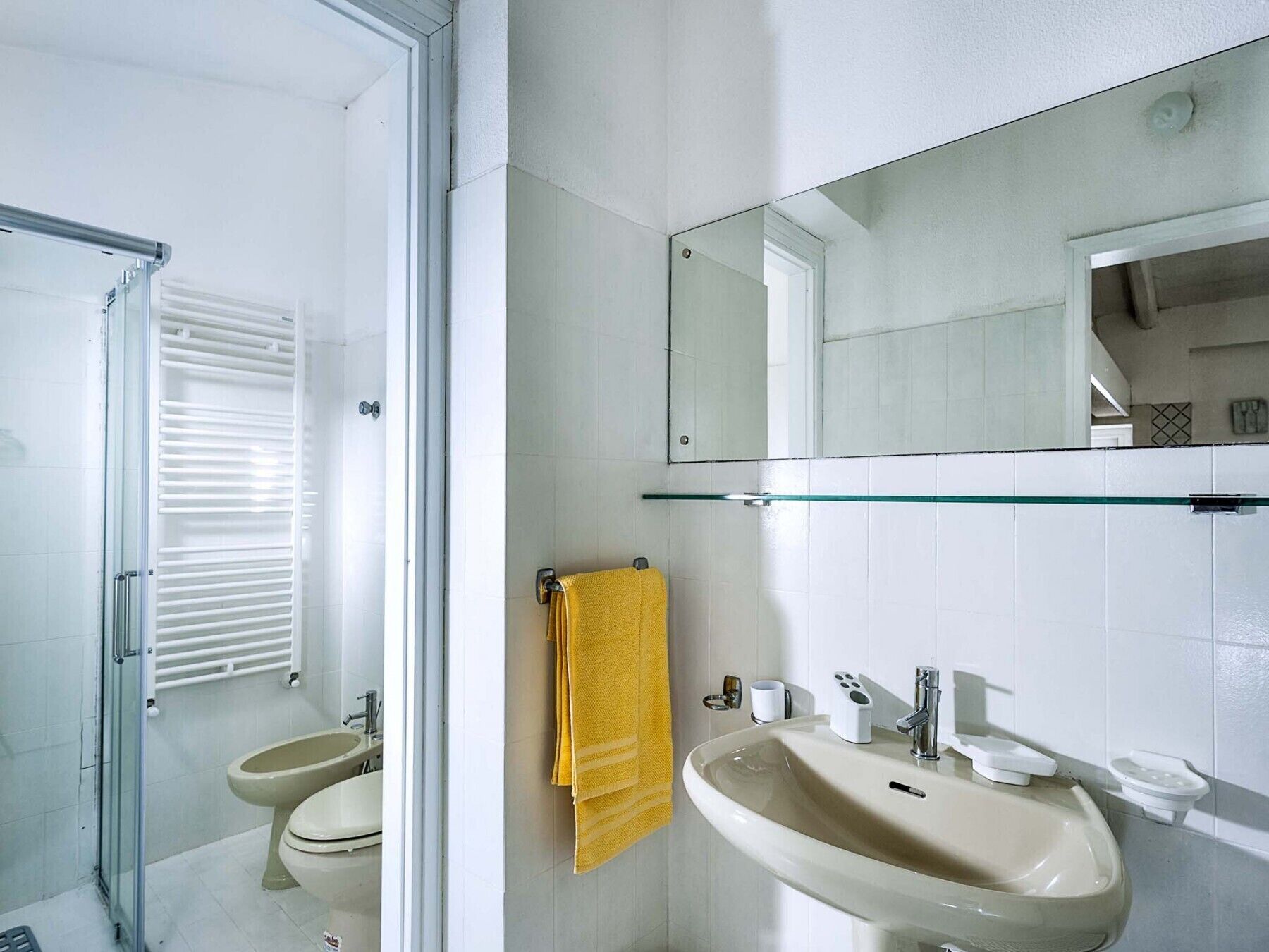 Ein modernes Badezimmer mit einer Duschkabine aus Glas, einem beigen Waschbecken und einem Spiegel darüber.