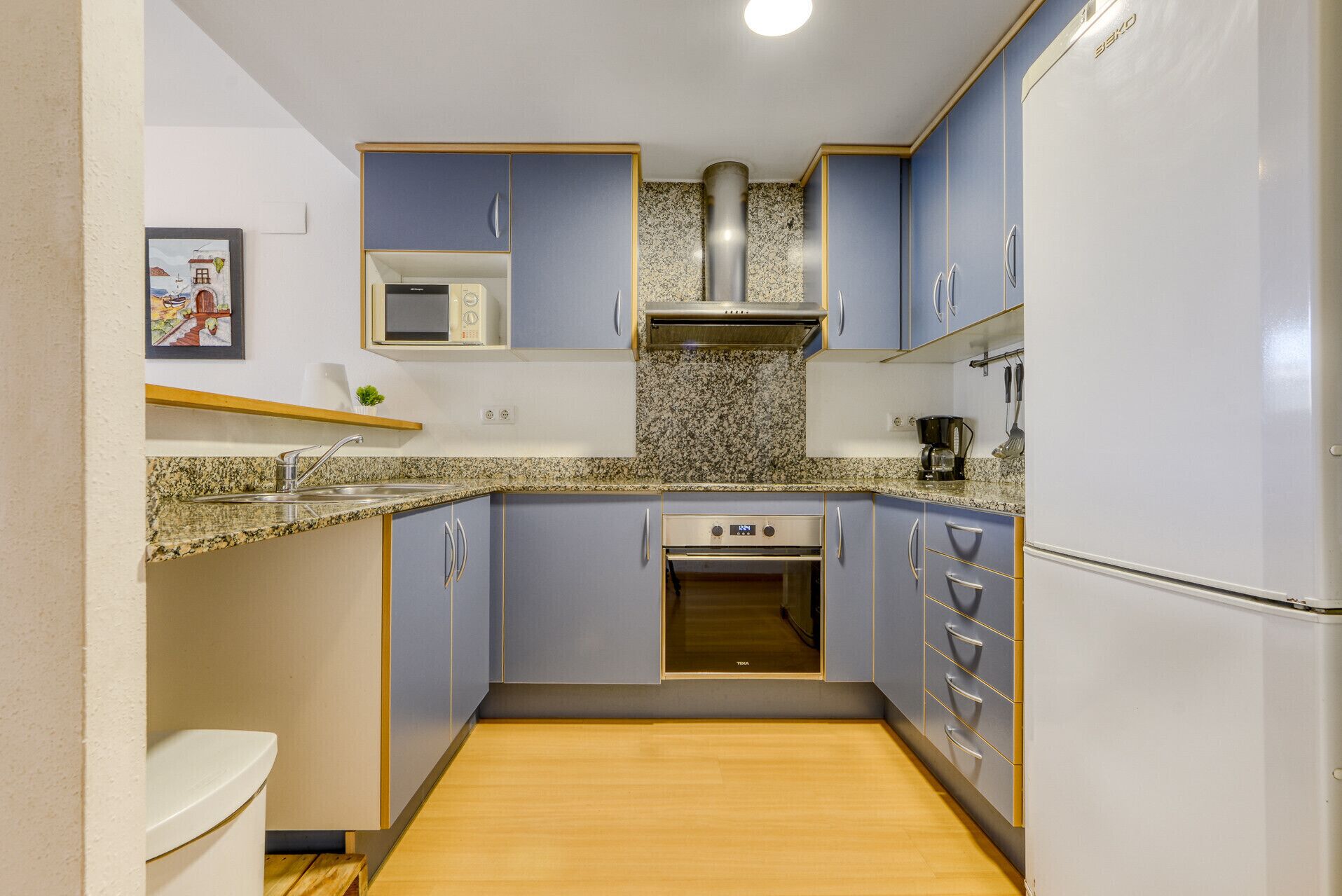 A compact kitchen with a microwave, oven, and stainless steel range hood.