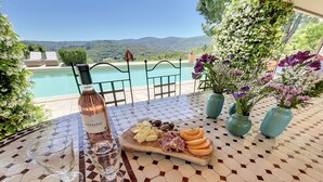 Une table avec une bouteille de vin, des verres, une planche de fromages et des fleurs.