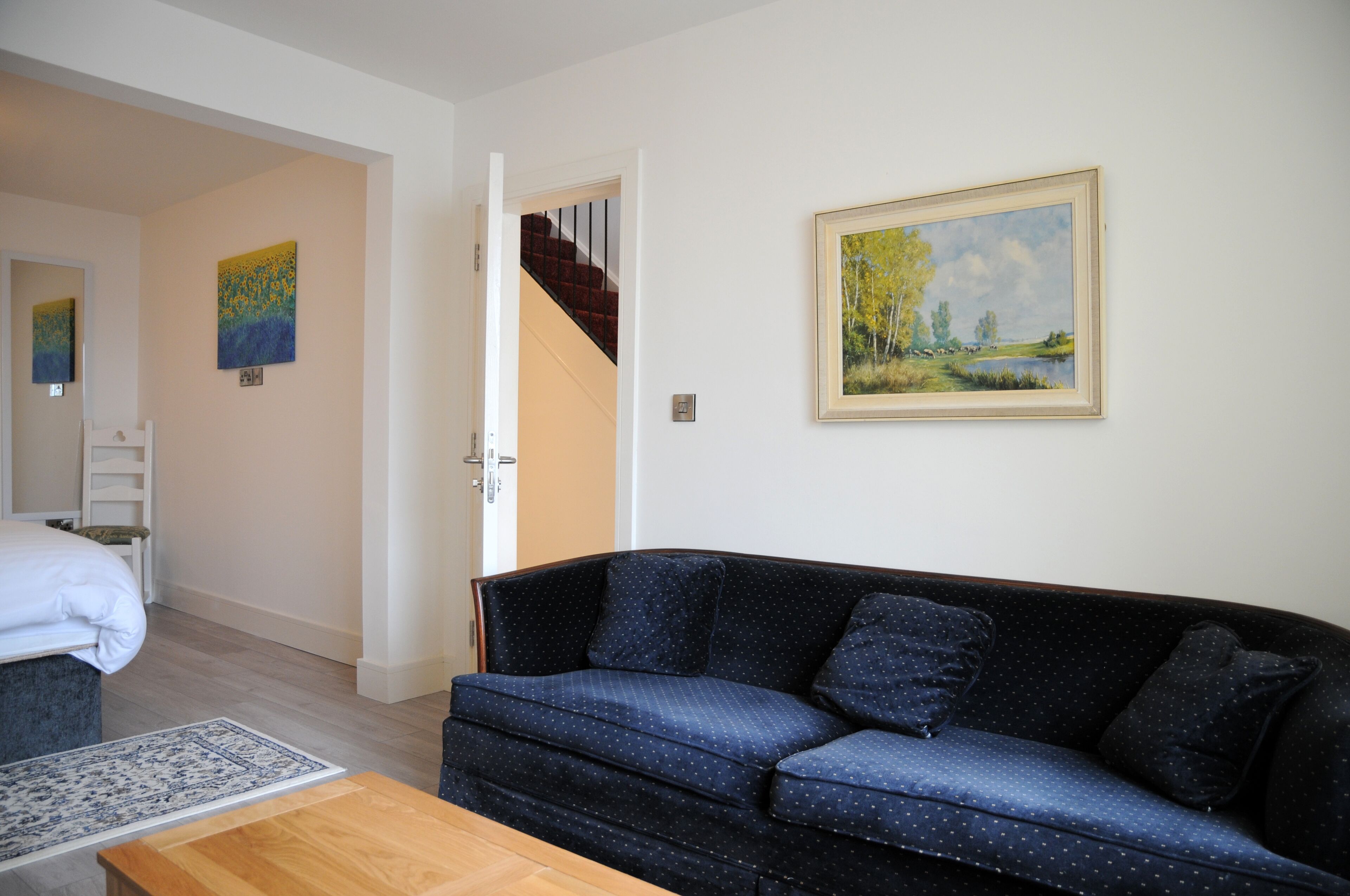 A living room with a dark blue sofa, a wooden coffee table, and a painting on the wall.