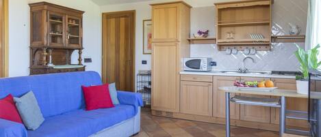 A compact kitchen with wooden cabinets, a microwave, and a small dining table.