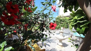 A garden with a fountain, a yellow chair, and red flowers. - ViVa Tropical (Buzanada, Arona)