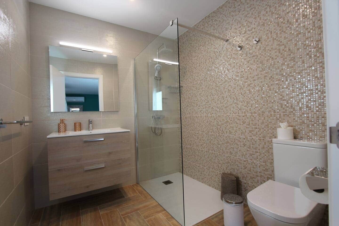 A modern bathroom with a glass shower enclosure, a vanity with a mirror, and a toilet.