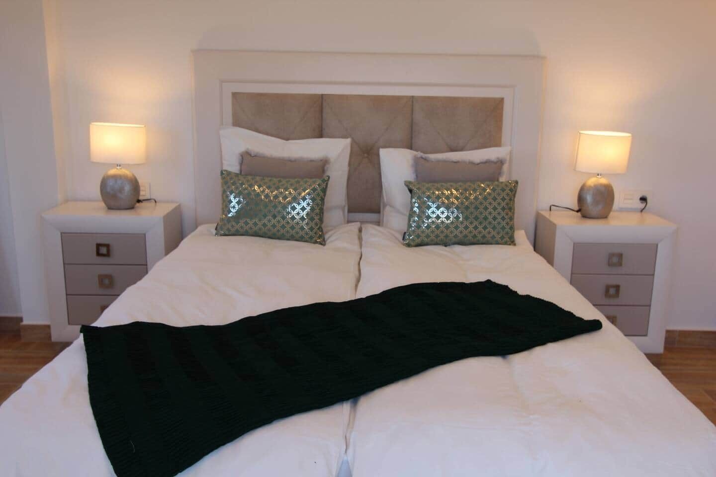 A double bed with a headboard, two bedside tables, and two lamps.