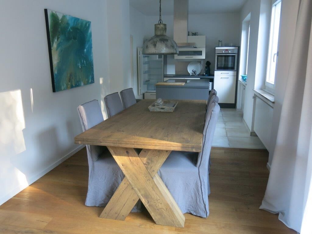 Eine moderne Küche mit weißen Schränken, einem Holztisch und einer hängenden Pendelleuchte.