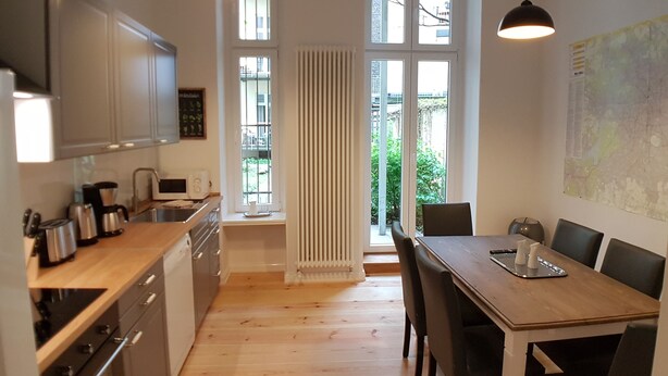 A modern kitchen with white cabinets, a wooden countertop, and a dining area with a table and chairs.