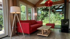 Una sala de estar moderna con un sofá rojo, una mesa de centro de madera y una lámpara de pie.