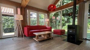 Una sala de estar moderna con un sofá rojo, una mesa de centro de madera y un mueble de entretenimiento negro.
