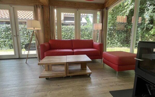 A room with a red sofa, a wooden coffee table, and a television.
