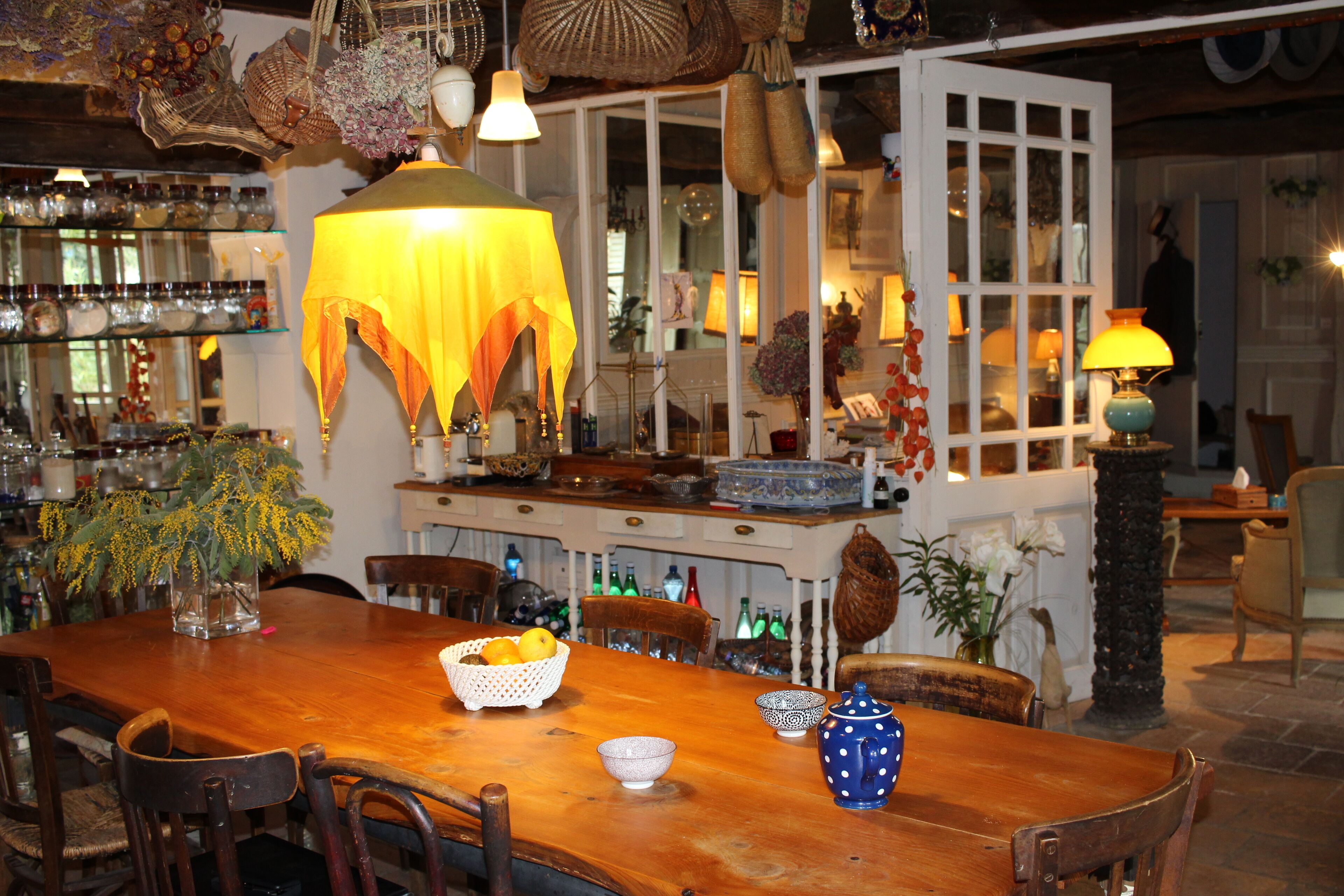 Una mesa de comedor de madera con sillas, una cesta de fruta y un florero con flores.