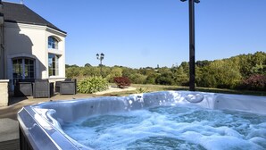 A hot tub with a view of a house and garden.