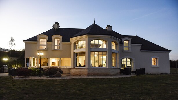 A large, two-story house with multiple windows and a well-lit exterior.