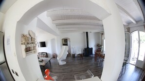 A spacious living area with a modern design, featuring a curved white chair, a dining table, and a fireplace.